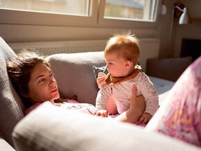 Woman lying on the couch in pyjamas with baby on her lap Woman lying on the couch in pyjamas with baby on her lap