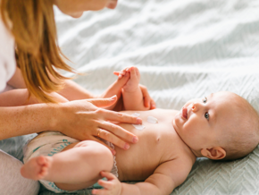 Mother massaging baby laying down with cream