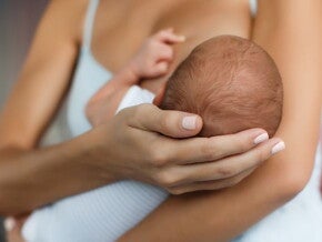 Woman holding small baby whilst breastfeeding Woman holding small baby whilst breastfeeding