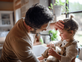Father putting hand on toddlers forehead to check for fever