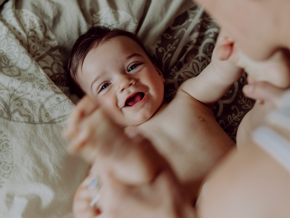 Baby smiling on a bed with his mother Baby smiling on a bed with his mother