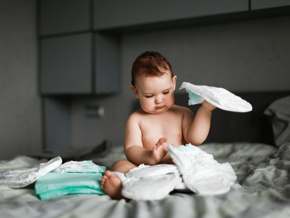 toddler on bed playing with nappies