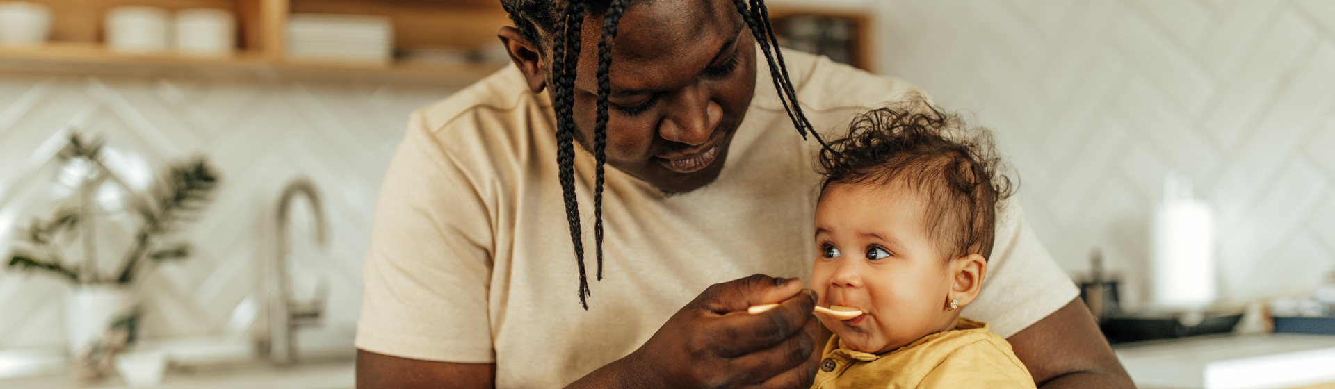 Mother feeding her baby with a yellow spoon